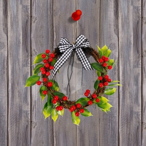 Artificial Christmas wreath with red berries, pine leaves, and plaid bow on rattan ring