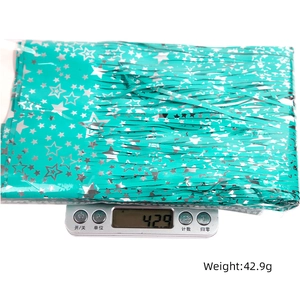 Teal tinsel fringe curtain with silver star patterns in plastic packaging on a scale