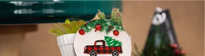 Close-up of circular Christmas ornament with red truck and pine tree pattern