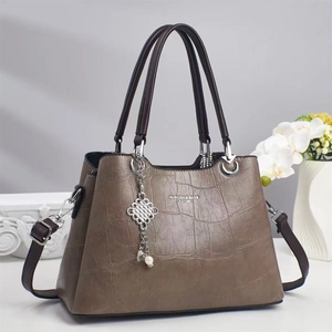 Détail du sac à main en cuir à texture crocodile avec breloque perle et boucles argentées