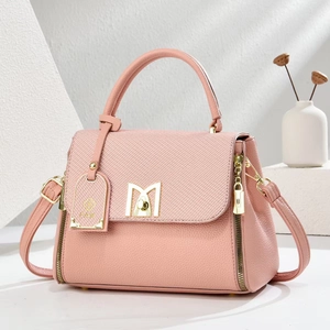 Pink crossbody bag in lychee pattern leather with a golden M clasp on white stand