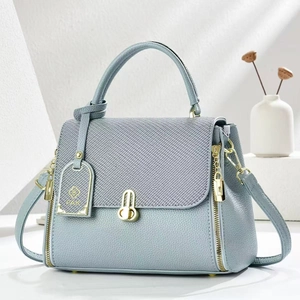 Detail of light blue crossbody bag with woven texture flap and gold metal hardware