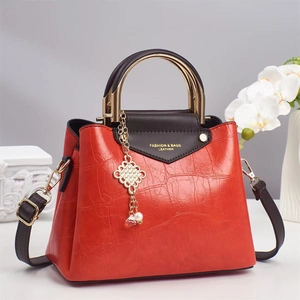 Red crocodile texture tote bag with golden handles and tassel on an elegant display