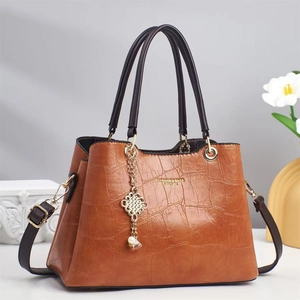 Detail of brown crocodile embossed leather handbag with gold chain and pearl charms