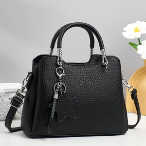 Detail of black pebbled leather handbag with silver star charm and twisted handle hardware