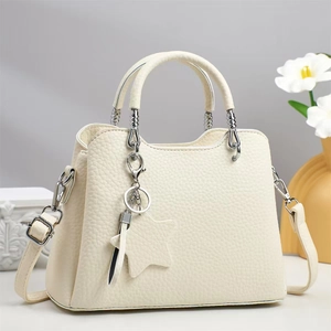 Detail of cream pebbled leather handbag with silver spiral hardware and star charm