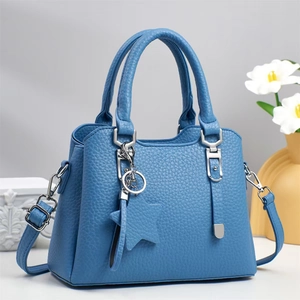 Blue lychee leather tote bag with silver hardware and star pendant in a bright scene