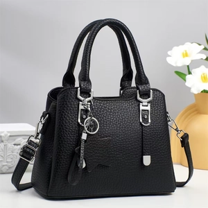 Detail of black lychee grain leather handbag with silver hardware and star pendant