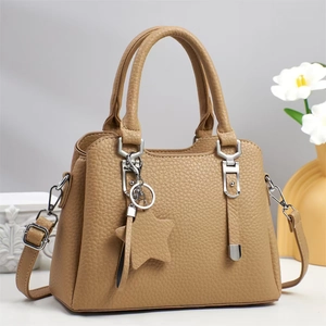 Detail view of khaki pebbled leather handbag with star pendant and silver hardware