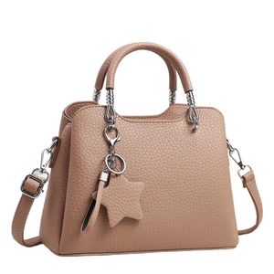 Light brown pebble leather handbag with twin handles and a star charm on white background
