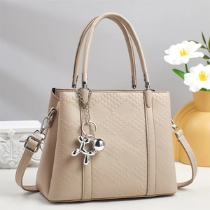 Detail der beige Handtasche mit geprägter Textur und silbernem Ballonhund-Anhänger