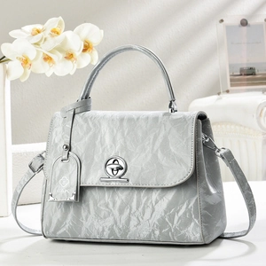 Detail of silver-grey handbag with unique pleated texture and oval metallic turn-lock