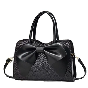Elegant black woven texture handbag featuring a large bow and adjustable shoulder strap
