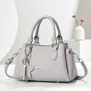 Detail of light gray lychee grain leather handbag with silver star chain charm accessory