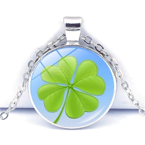 Détail d'un pendentif trèfle argenté avec une pierre précieuse en verre vert