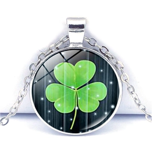 Gros plan d'un collier pendentif trèfle argenté avec motif vert et dôme en verre poli