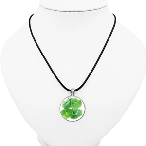 Silver four-leaf clover pendant necklace with green glass gem on a white mannequin
