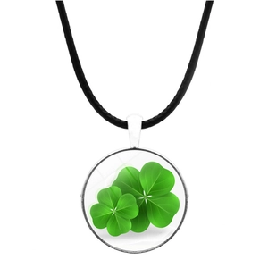 Detailed macro view of a silver-framed glass pendant with green four-leaf clover motifs