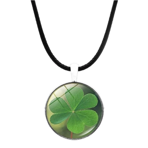 Macro view of four-leaf clover pendant with clear glass cabochon and black cord necklace