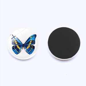 Detailed view of the 25mm round glass fridge magnet with a blue butterfly design