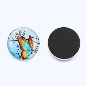 Macro detail of round crystal glass fridge magnet showing colorful butterfly design and magnetic back