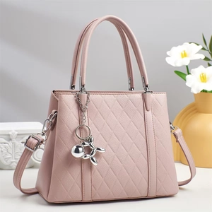 Close-up of quilted pink tote bag with silver balloon dog charm and adjustable strap