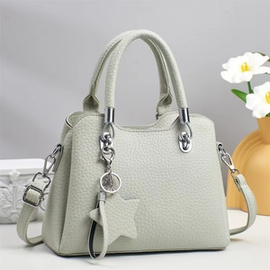 Détail du sac à main vert clair en cuir grainé avec breloque étoile et détails argent