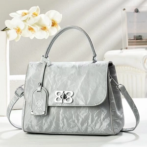 Detail of silver pleated leather bag with butterfly metal clasp and adjustable strap