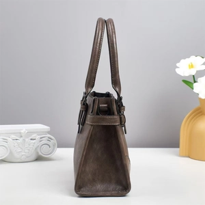 Detail view of the vintage brown leather handbag with side buckle and metallic ring