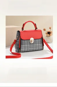 Detail of red and plaid handbag with golden rotating lock and elegant leather handle