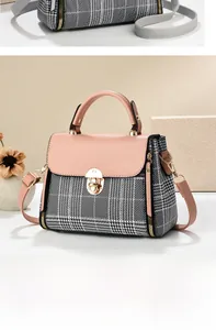 Detailed view of pink pebble leather flap and plaid fabric stitching on handbag