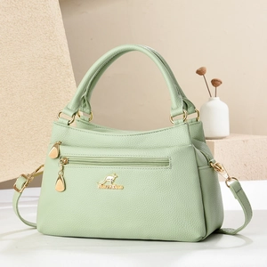 Nahaufnahme der hellgrünen Litschileder-Handtasche mit goldenem Logo und Reißverschluss