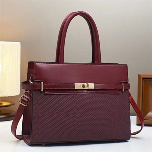 Detail of burgundy crossbody bag featuring woven texture panel and gold swivel lock