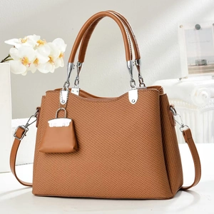 Close-up of brown textured woven handbag with silver hardware and orchid decor