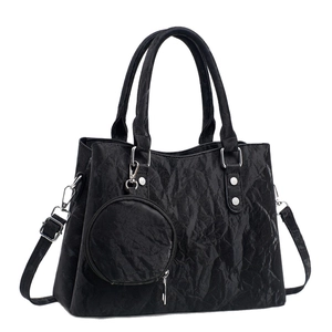 Elegant black textured handbag with top handles, crossbody strap and a small round coin pouch