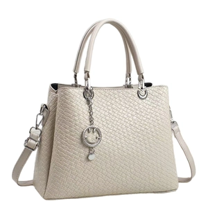 Chic cream woven tote bag with dual handles, crossbody strap, and smiley face pendant