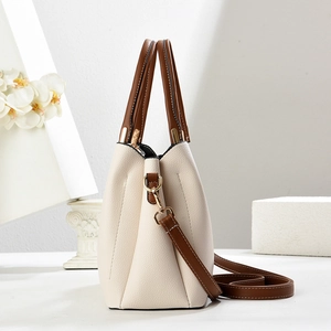Detailed view of the creamy white lychee grain leather handbag with brown handles
