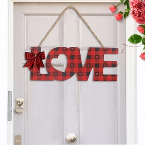 Detail of red buffalo plaid LOVE sign hanging on a white door with rose accents