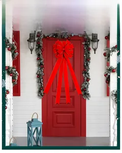Large red velvet Christmas bow with gold stitching hung on a holiday decorated door