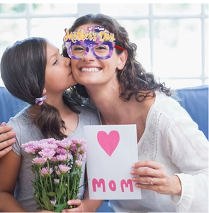 A close-up of a mother wearing purple floral Mother's Day party glasses with a child
