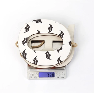 Close-up of wooden Halloween letter ornament with black bat print on digital scale