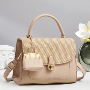 Close-up of beige leather handbag with woven texture flap and golden round metal clasp
