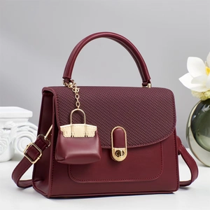 Detail of burgundy leather handbag showing the gold oval twist lock and woven texture