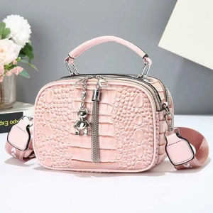 Pink crocodile pattern handbag detail with double zippers and silver bear pendant