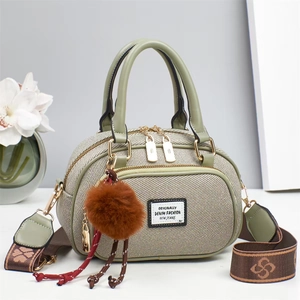 Detail of grey-green denim texture bag with jacquard strap and plush pendant decor