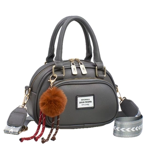 Graue Handtasche mit Litschi-Maserung, breitem Jacquard-Gurt und Plüsch-Anhänger