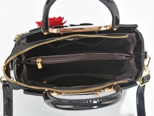 Top-down macro view showing multi-compartment interior and gold hardware of the black bag