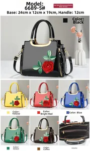 Detail view of glossy patent leather handbag with 3D rose embroidery and metal handles