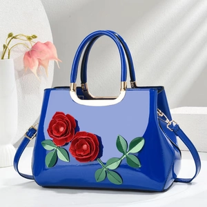 Detail of bright blue patent leather handbag with 3D red roses and gold metal handle