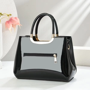 Glossy black patent leather tote bag with gold metal handles and rear zipper pocket